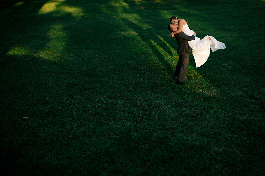 groom lifting bride up in sliver of sunlight