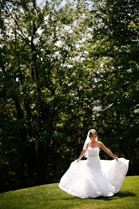 Bridal portrait of bride fixing her dress in the sun