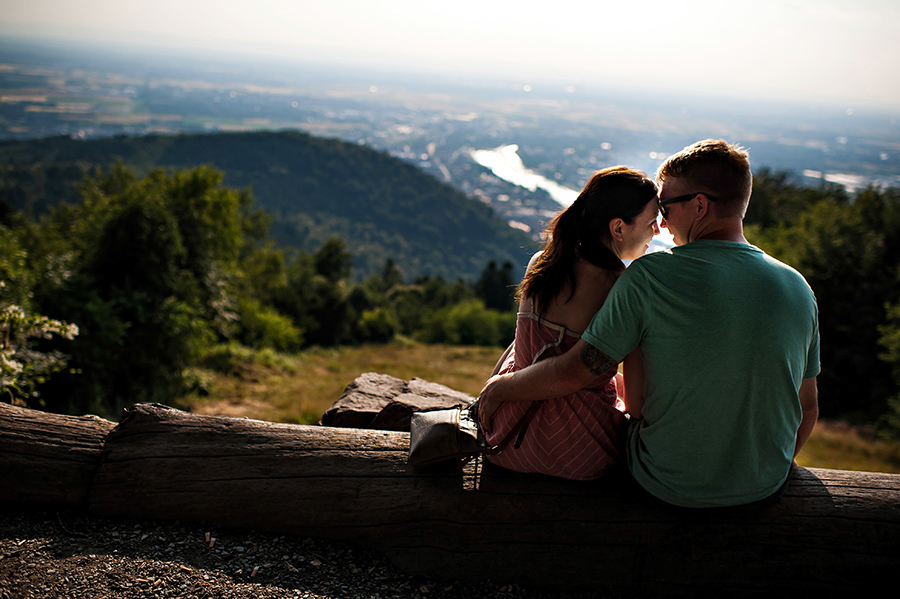 Bride and groom snuggle on a log over looking the German town of Heidelberg the day before their wedding.