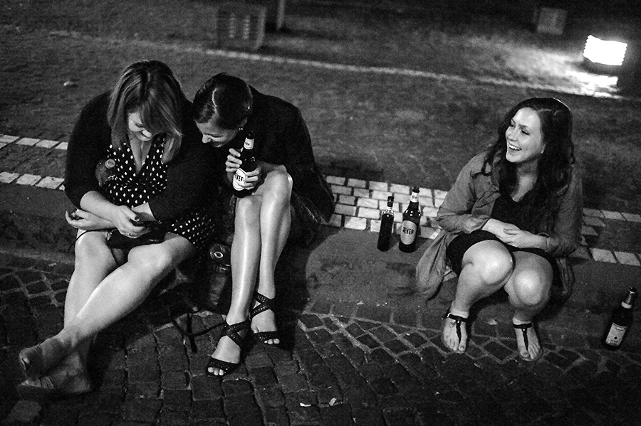 Bride and wedding guests relax on Heidelberg streets at night.