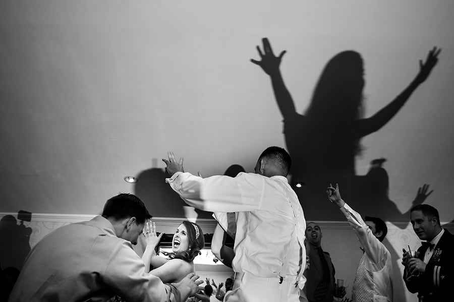 Bride dances with guests as a shadow is cast on the wall.