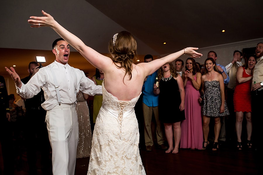 Bride and groom sing with open arms during wedding reception.