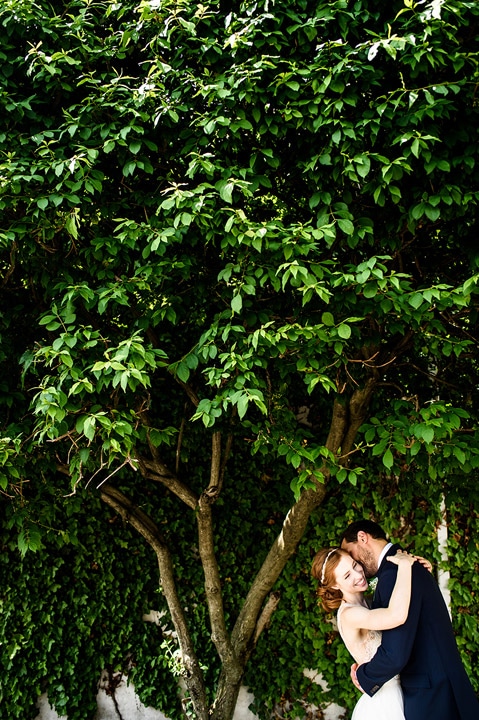 Bride and groom hugging under and tree.