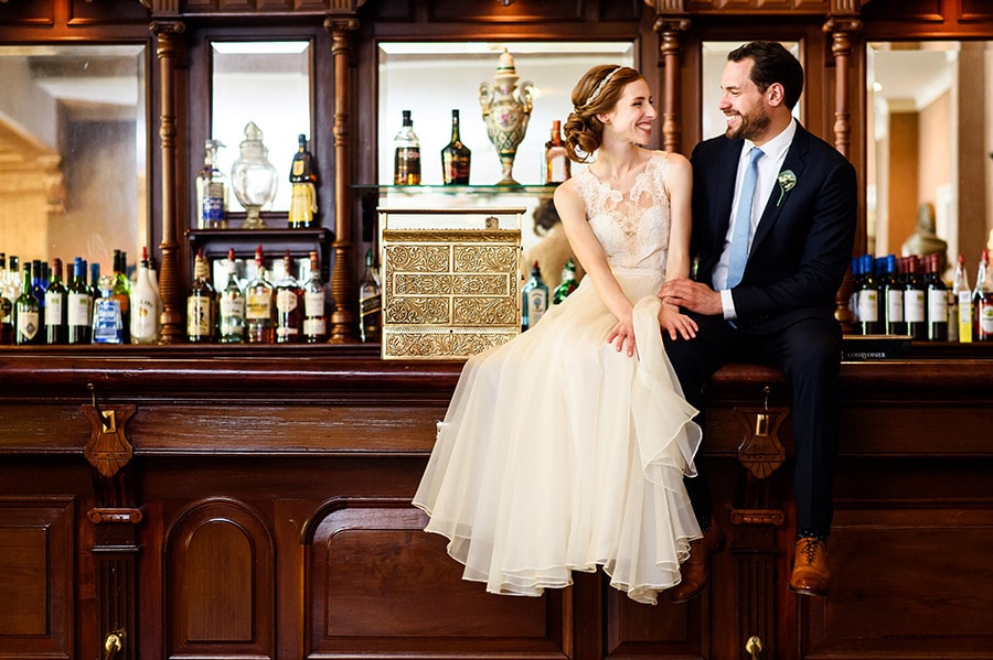 Bride and groom sitting on a bar.