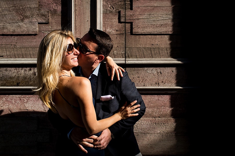 Groom to be kissing his bride to be on the cheek in the sunlight!