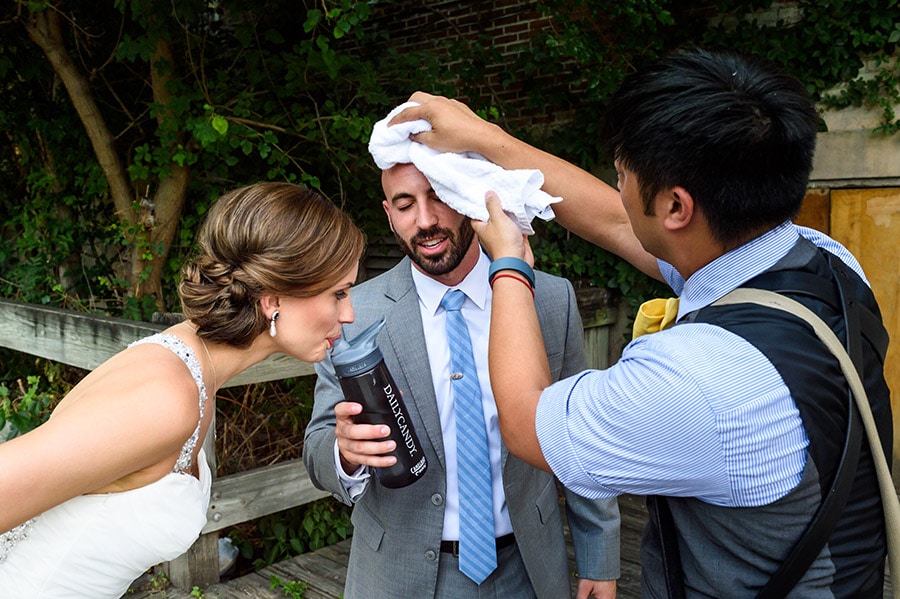 Philadelphia Wedding Photographer wiping grooms sweat as bride drinks water.