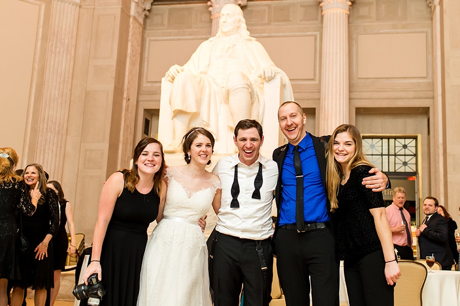Philadelphia photographer poses with bride and groom at Franklin Institute on their wedding day.