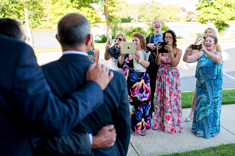 Photographer standing behind weddings guests taking photos.