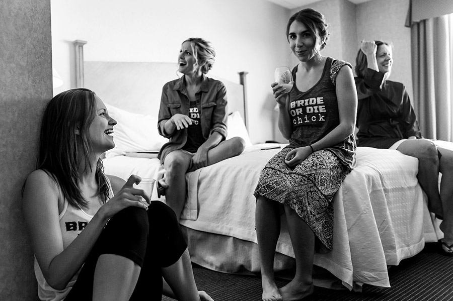 Bride and bridesmaids laugh while they get ready on wedding day.