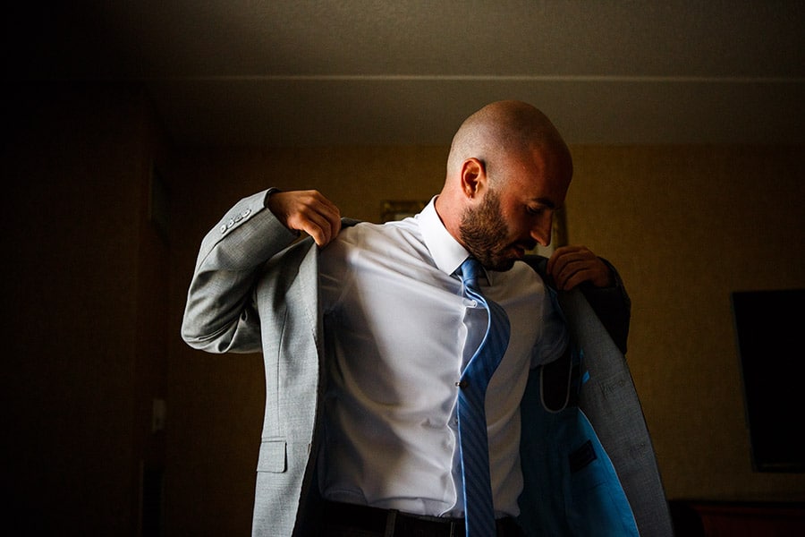 Groom put his suit jacket on on his wedding day.