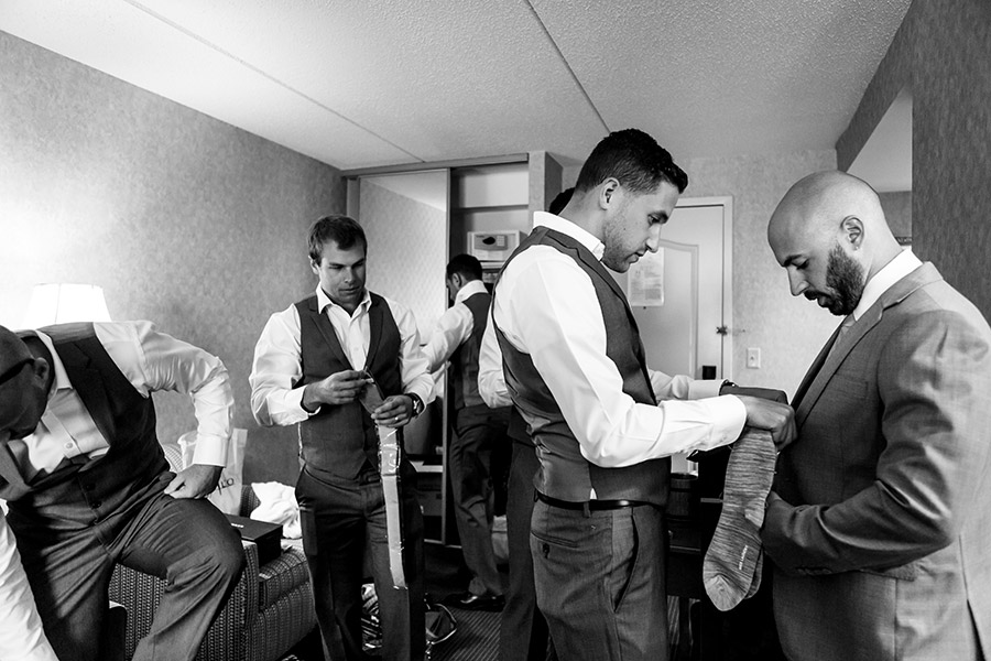 Groomsmen helps groom with tie.