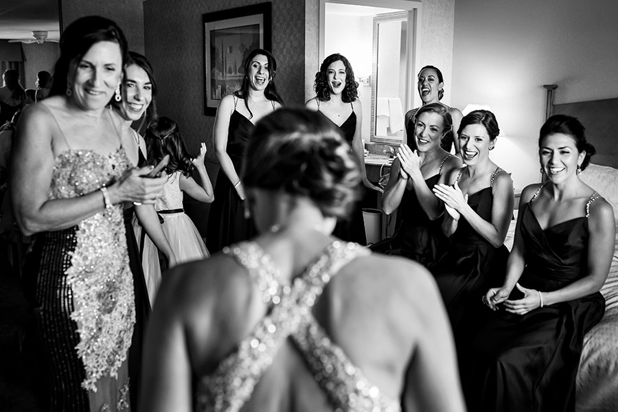 Excited bridesmaids see bride in her wedding dress for the first time.