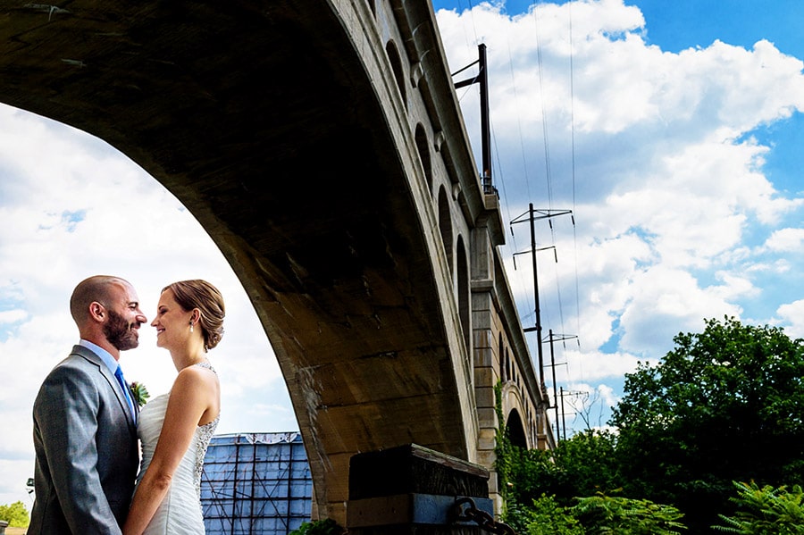 Bride and groom under a bridge on wedding day.