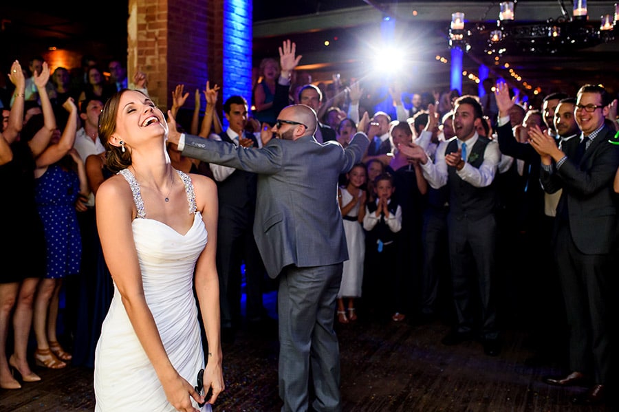 Bride laughs as groom entices weddings guests.