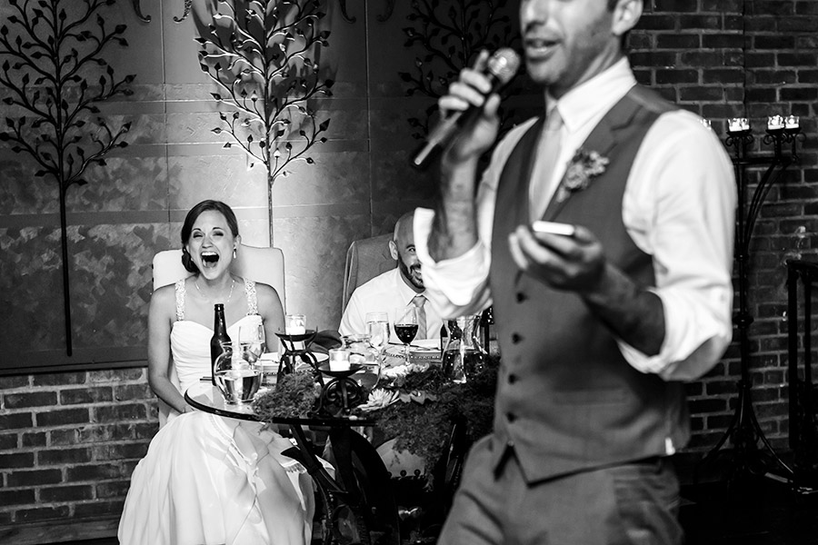 Bride and groom laugh hysterically at Best Man speech.