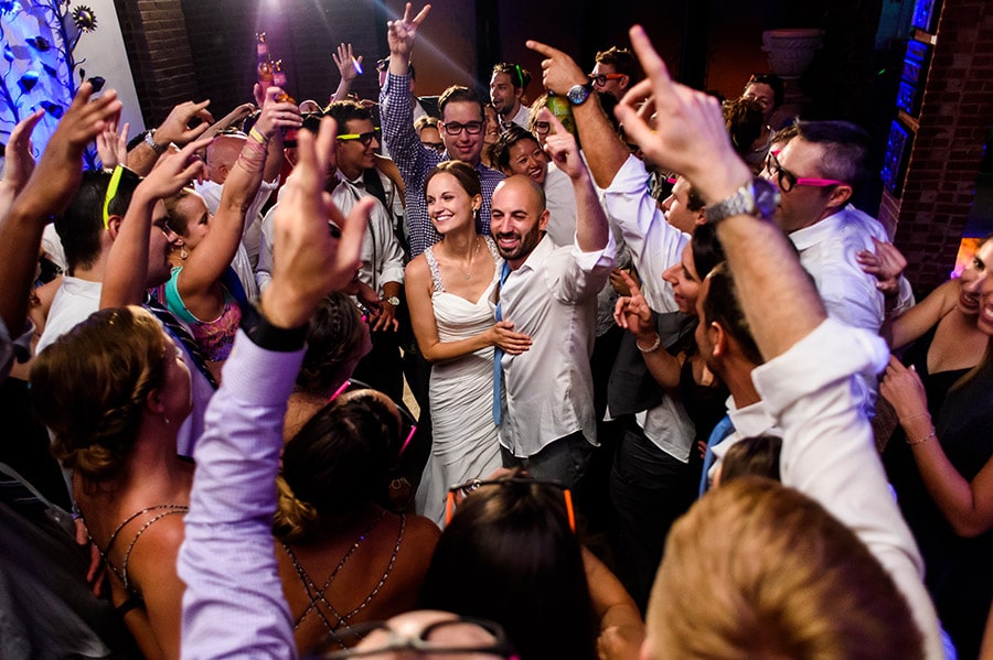 Wedding guests throw arms in the air as they surround bride and groom!