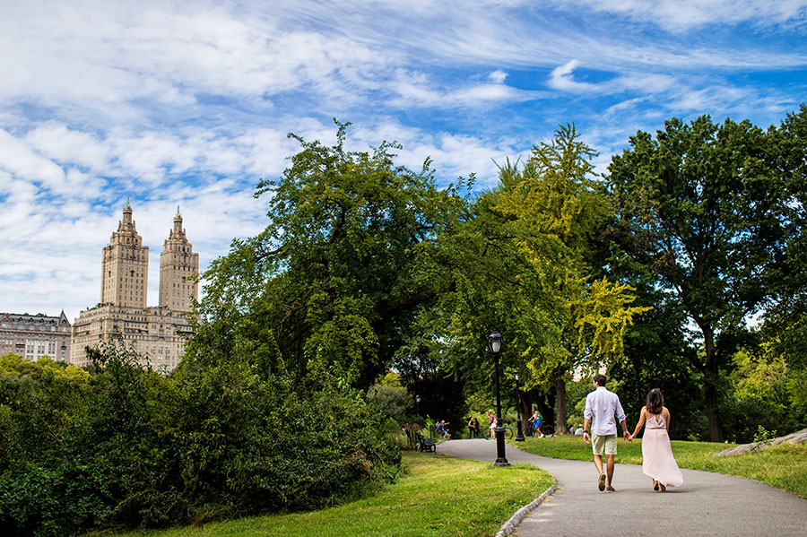 A Bride-to-be and Groom-to-be hold hands and walk through Central Park during their engagement session.