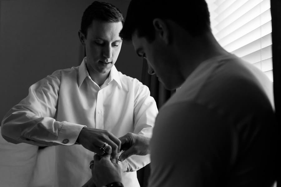 Best man helping groom with his cufflinks on his wedding day.