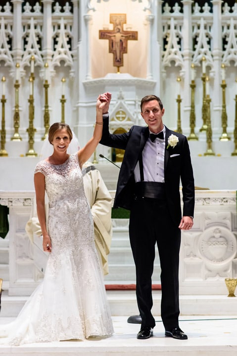 Bride and groom raise their arms and celebrate being named husband and wife.