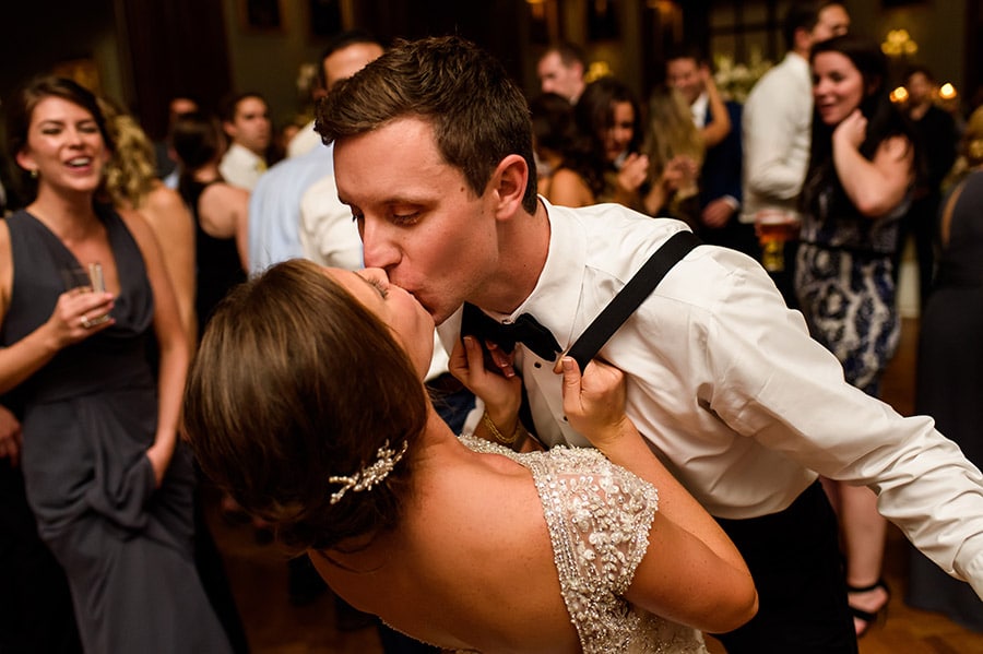 Bride pulling groom into kiss him by the suspenders!
