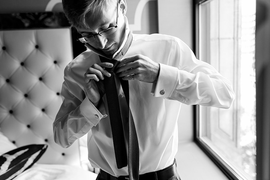 Groom tying his tie on wedding day.