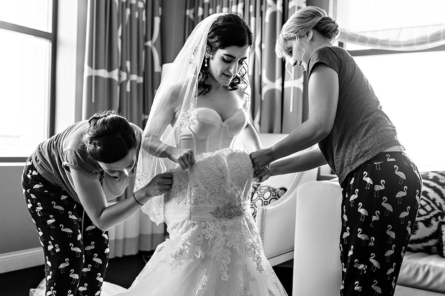 Bridesmaids helping bride put her dress on at Hotel Monaco in Philadelphia, PA.