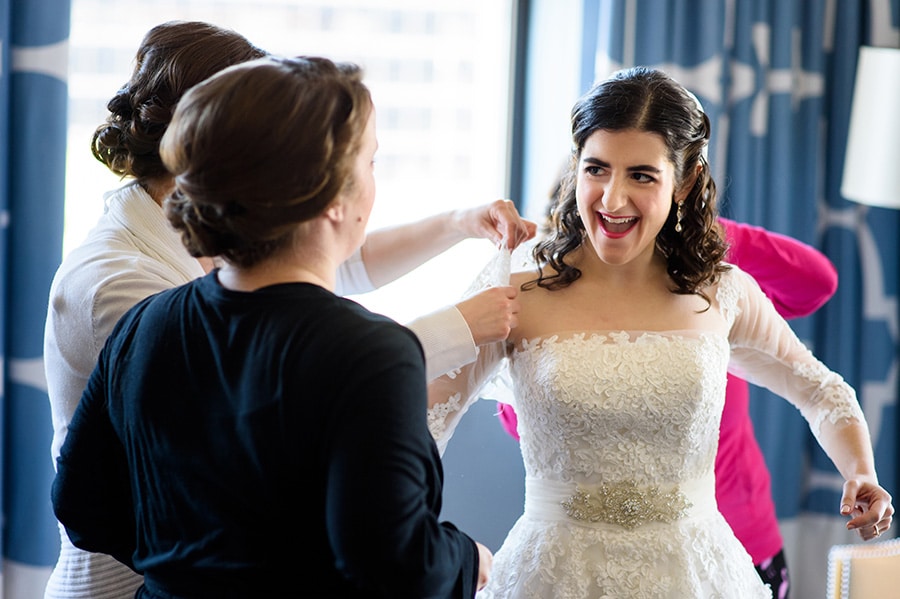 Excited bride putting a lace jacket on.