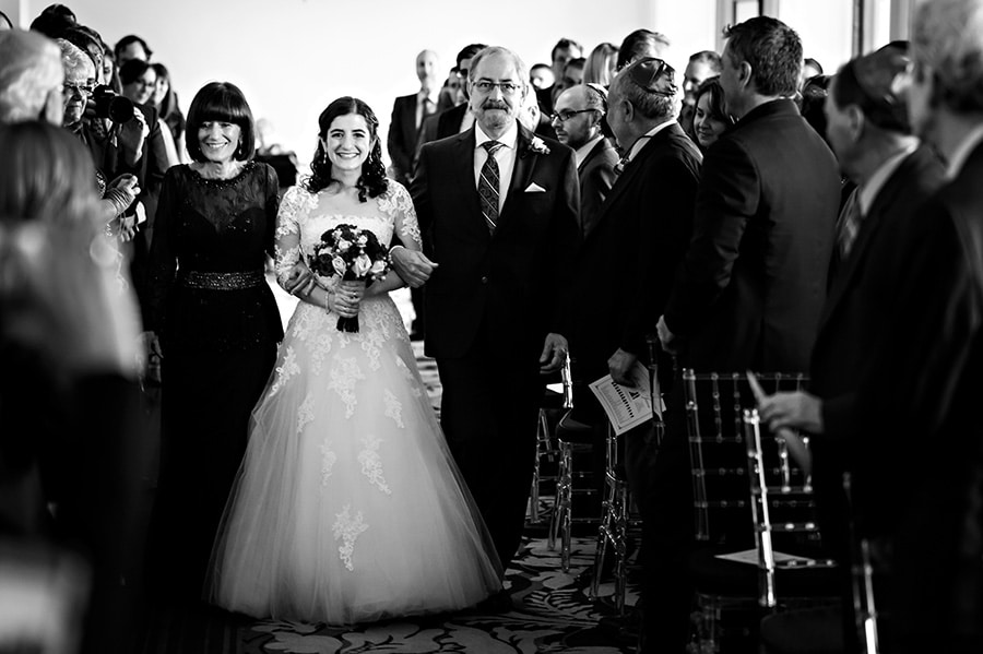 The bride and her parents walk down the aisle during a Jewish ceremony at The Downtown Club in Philadelphia, PA.