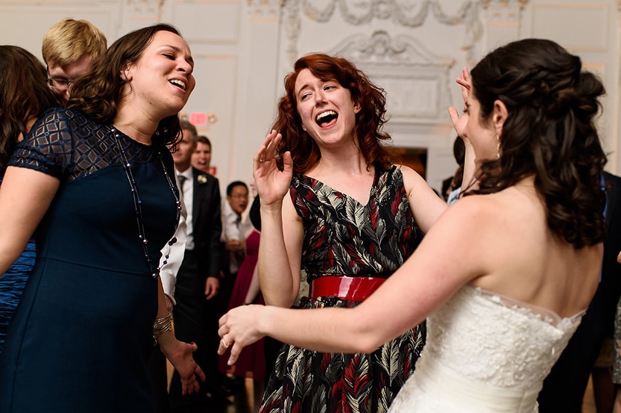 Bride and two wedding guests sing along to a song on the dance floor.