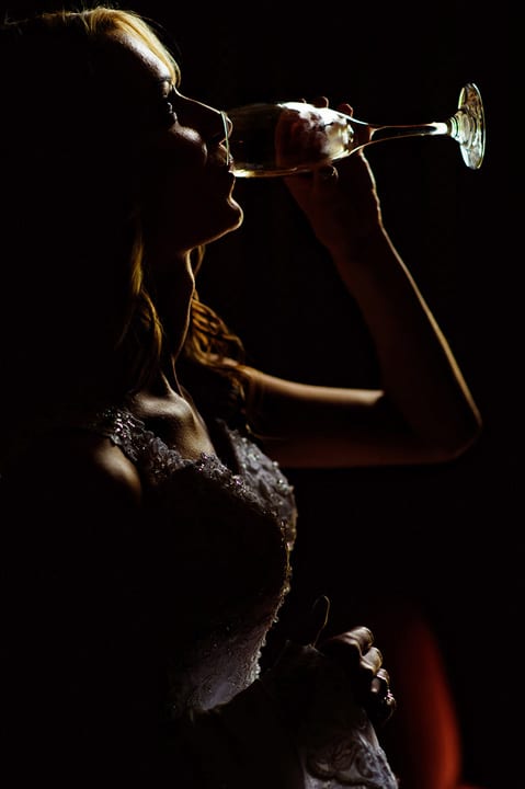 Moody image of a bride drinking from her champagne glass.