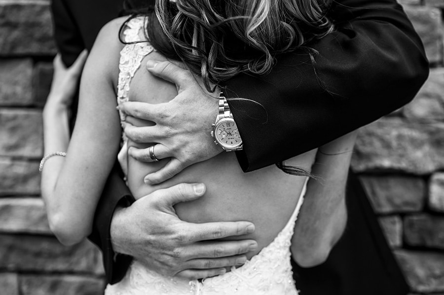 Groom's hands squeeze bride tightly.