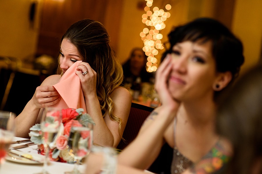 Wedding guests wipe tears away during wedding maid of honor speech.