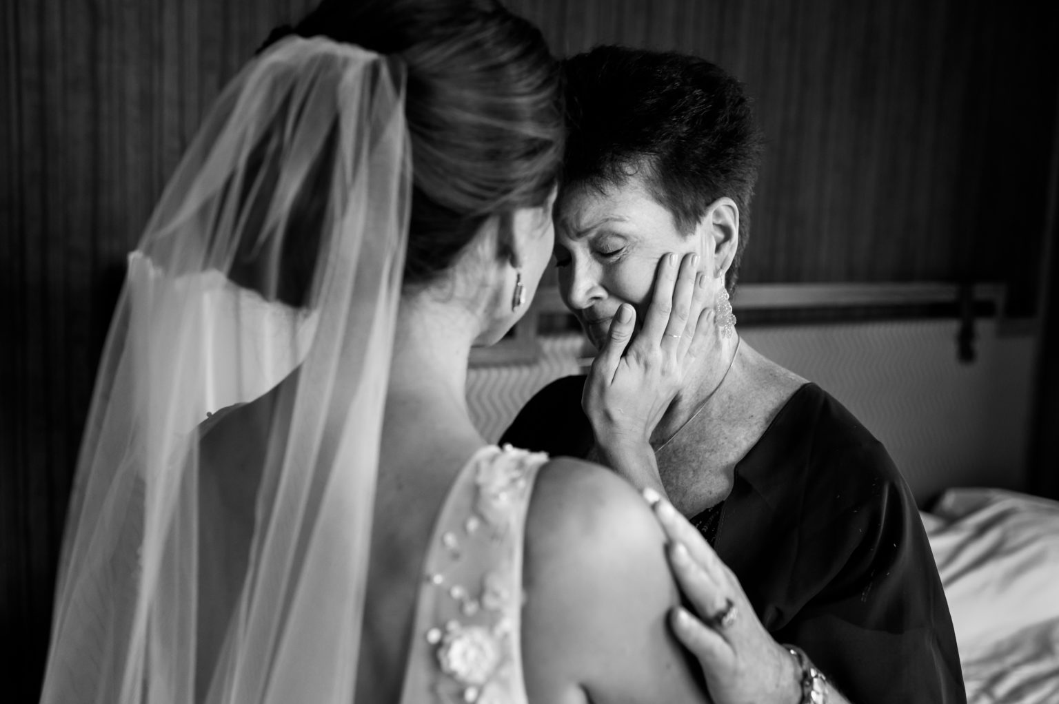 Bride places had on crying mom's cheek to console her after seeing her in her dress for the first time.
